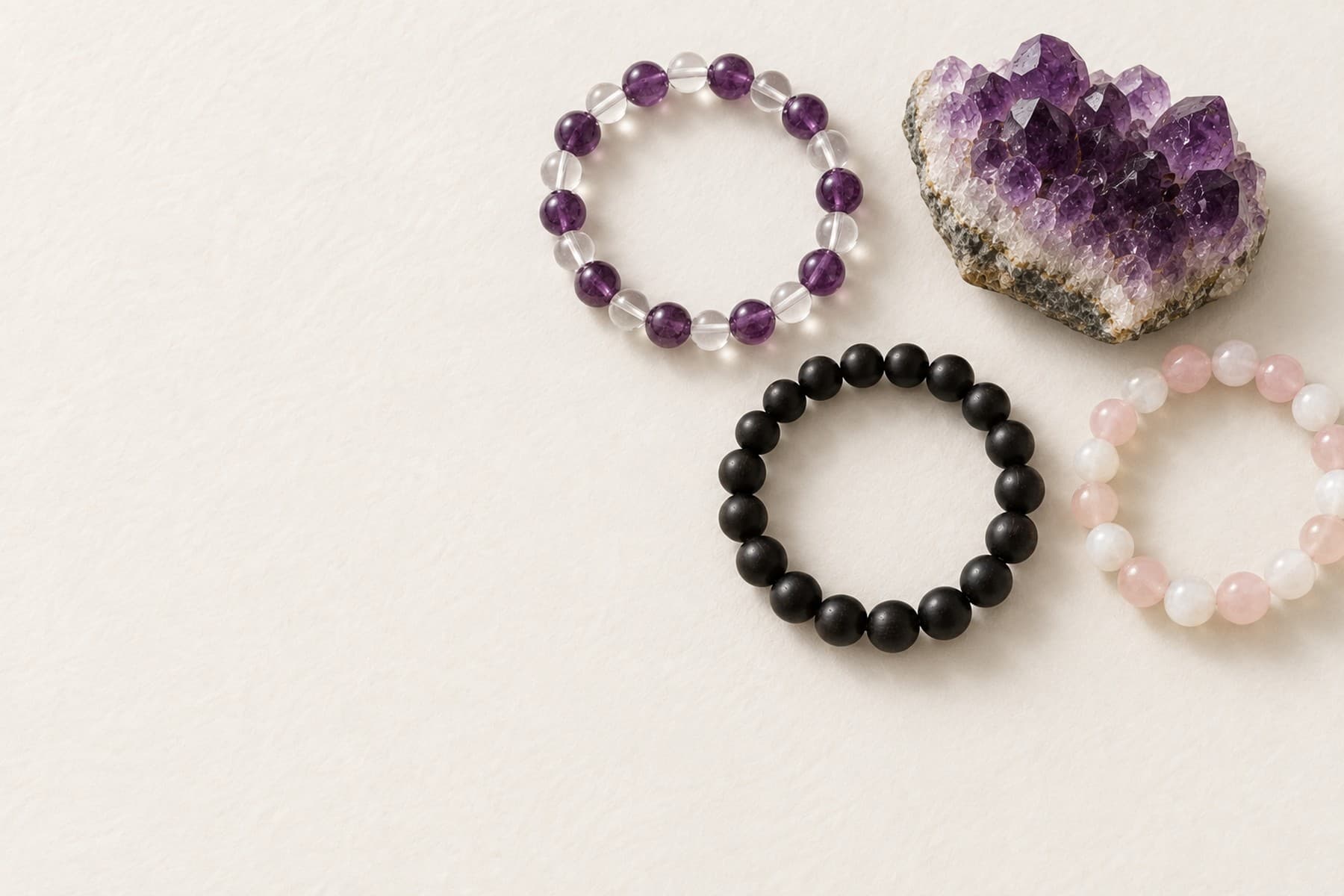 Gemstone bracelets and a raw amethyst cluster on bone paper